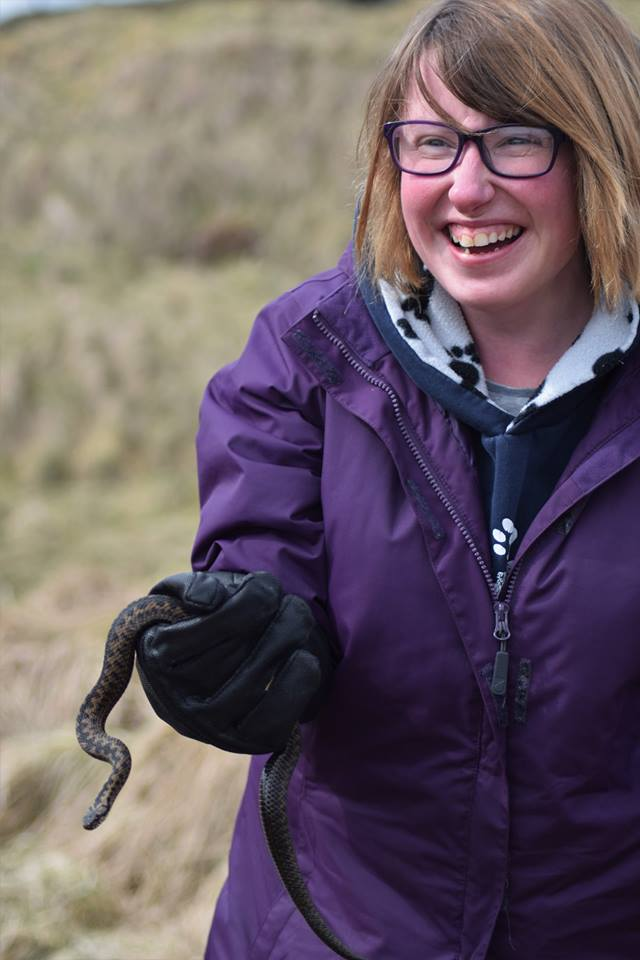 Image description: Ellie in purple coat holding an adder under license during her first year of university. 